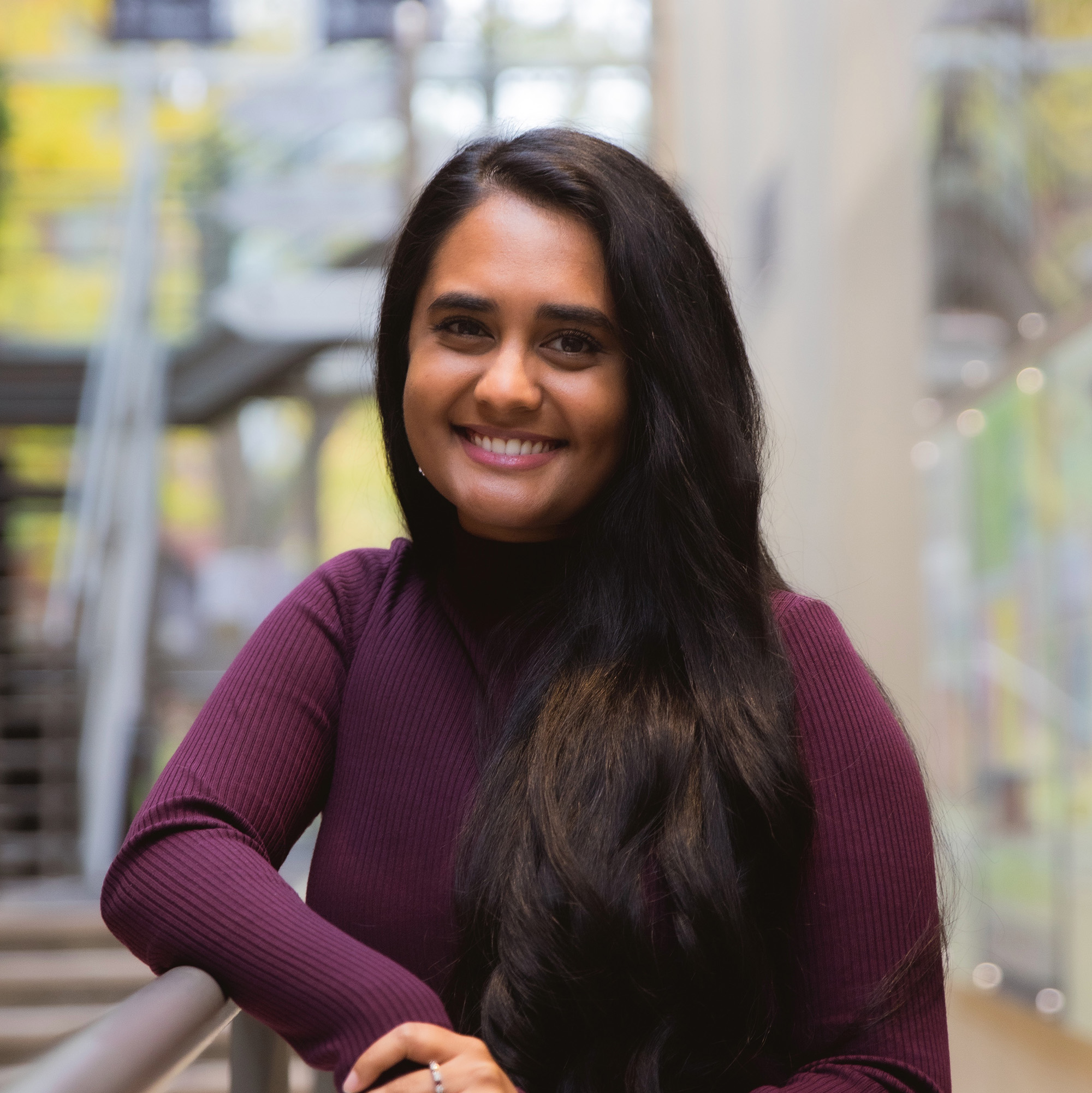 Dianthi Fernando stands in the Innis College lobby smiling at the camera